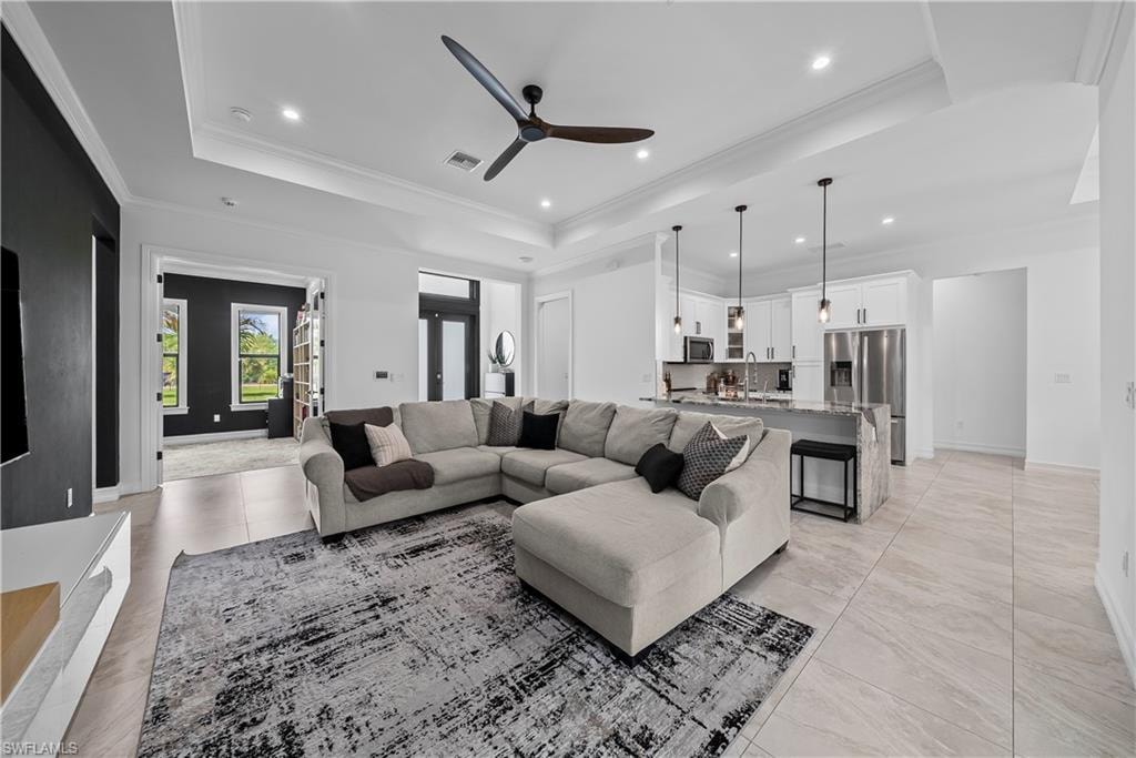 Living area featuring ceiling fan, crown molding, a tray ceiling, and recessed lighting