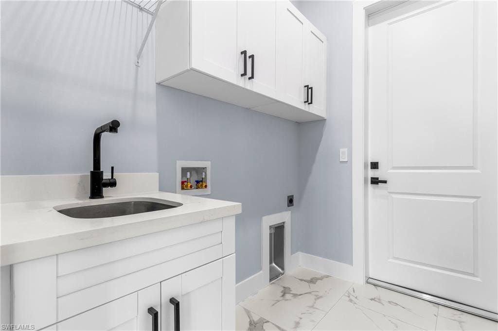 Laundry room featuring cabinet space, electric dryer hookup, hookup for a washing machine, and light marble finish floors