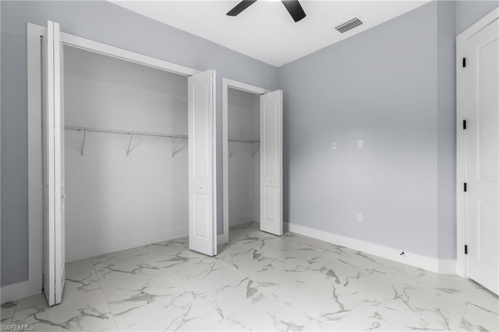 Unfurnished bedroom with a closet, light marble finish floors, and ceiling fan