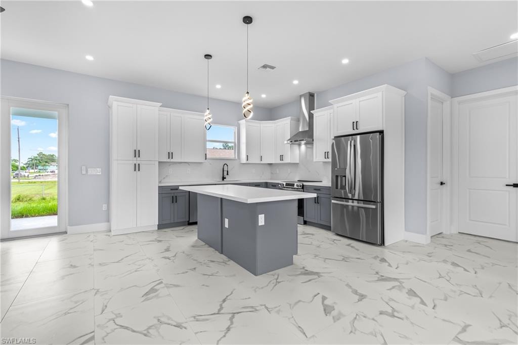 Kitchen featuring gray cabinets, white cabinets, stainless steel appliances, decorative light fixtures, and tasteful backsplash