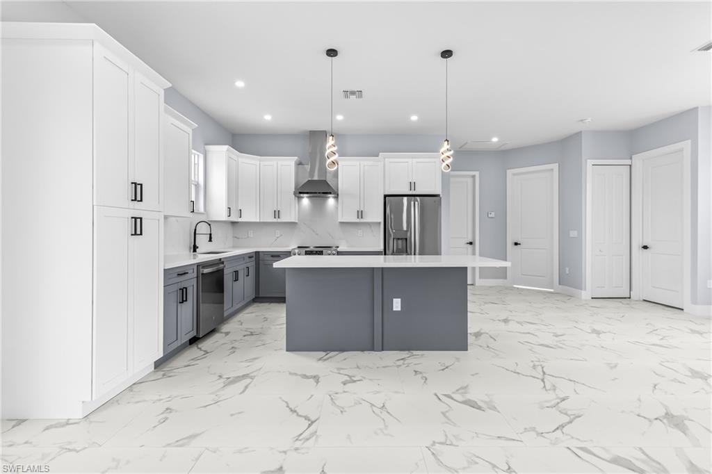 Kitchen with gray cabinets, white cabinets, tasteful backsplash, a kitchen island, and hanging light fixtures