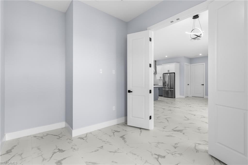 Empty room with light marble finish flooring and a chandelier