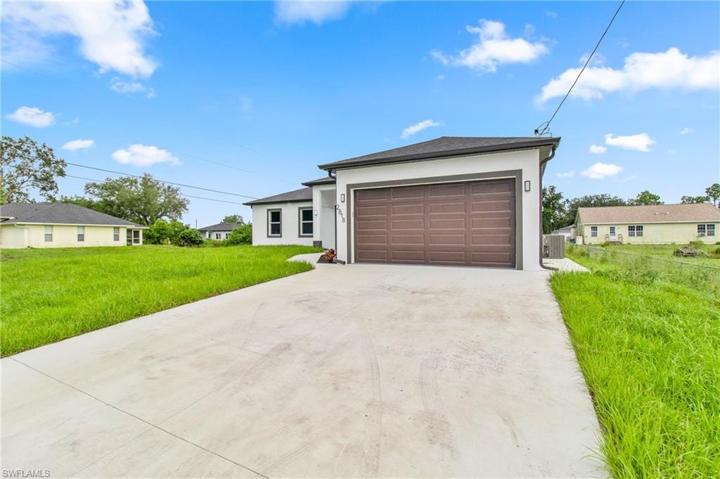 View of front of property featuring concrete driveway, stucco siding, a front yard, and a garage