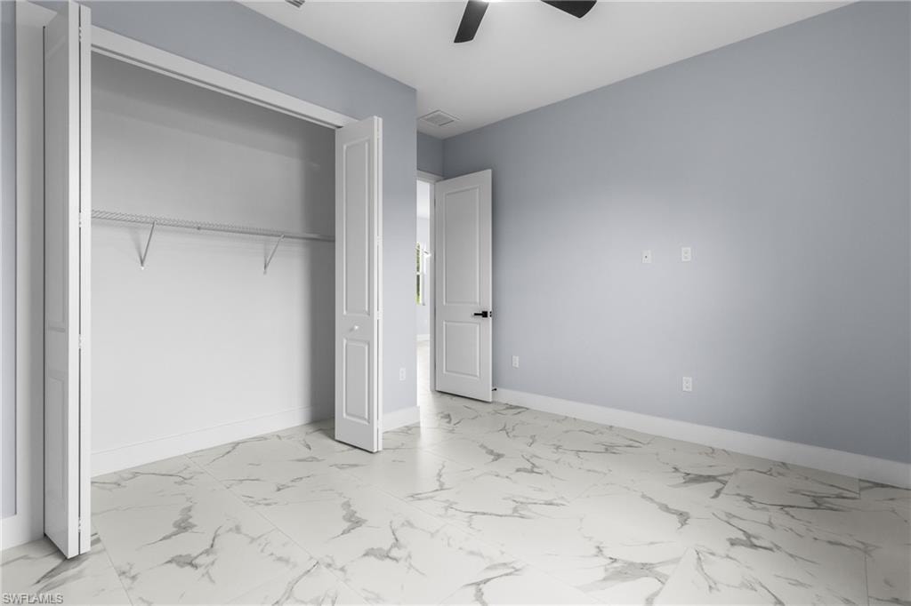 Unfurnished bedroom with light marble finish floors, a ceiling fan, and a closet