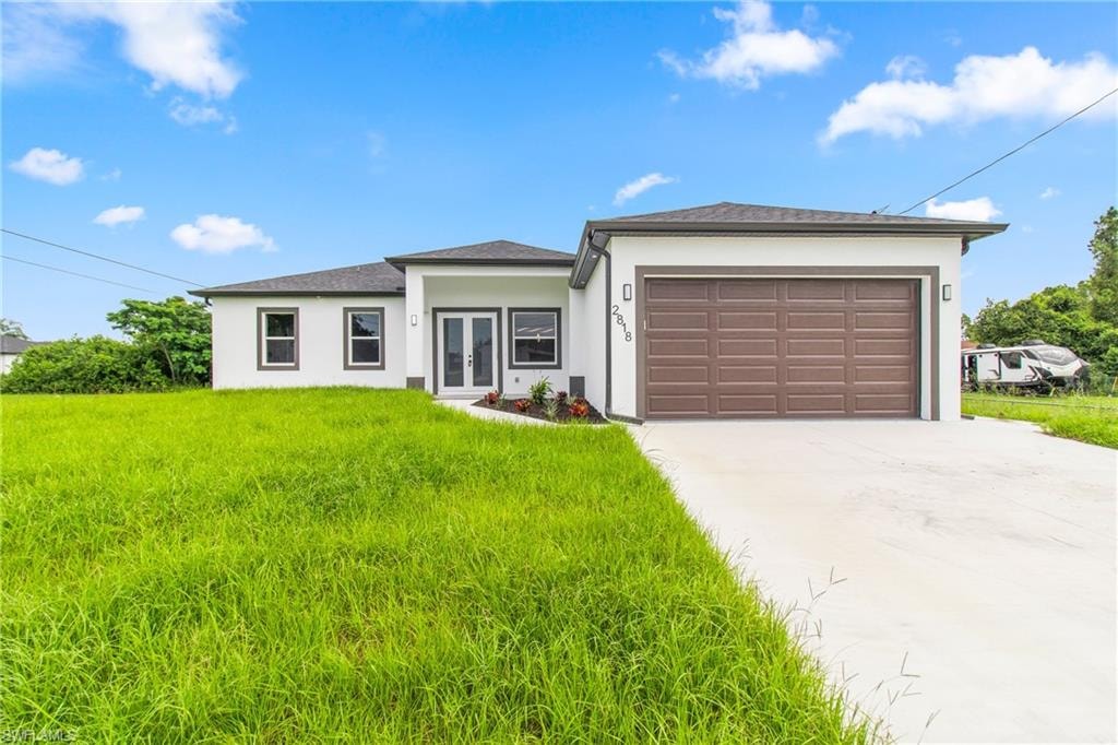 Prairie-style house featuring concrete driveway, stucco siding, an attached garage, a front yard, and a shingled roof