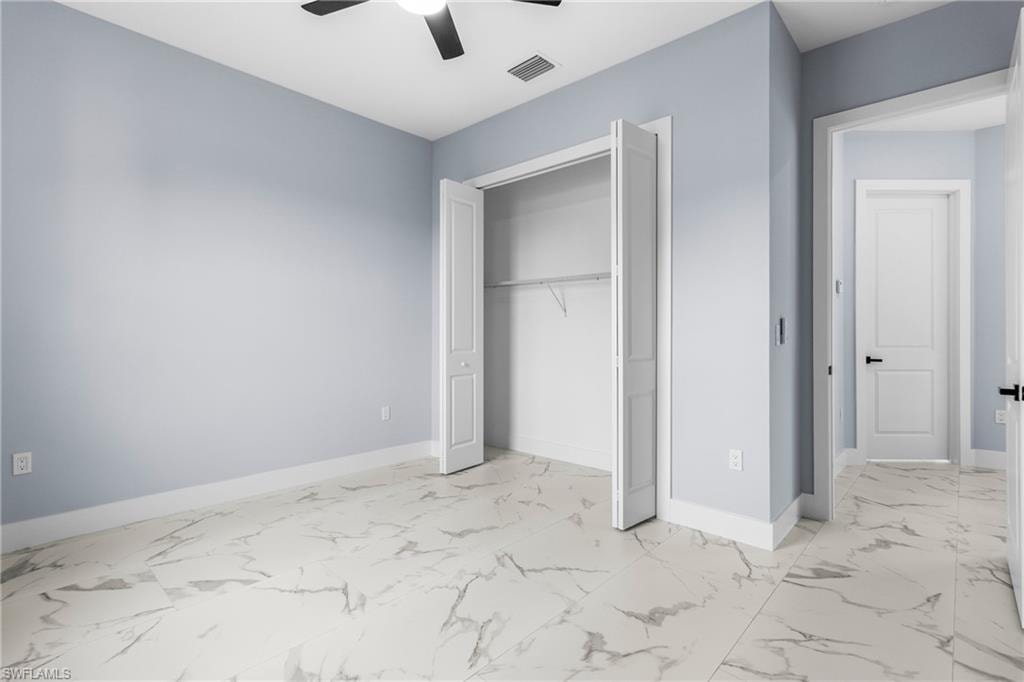 Unfurnished bedroom with light marble finish floors, a closet, and ceiling fan