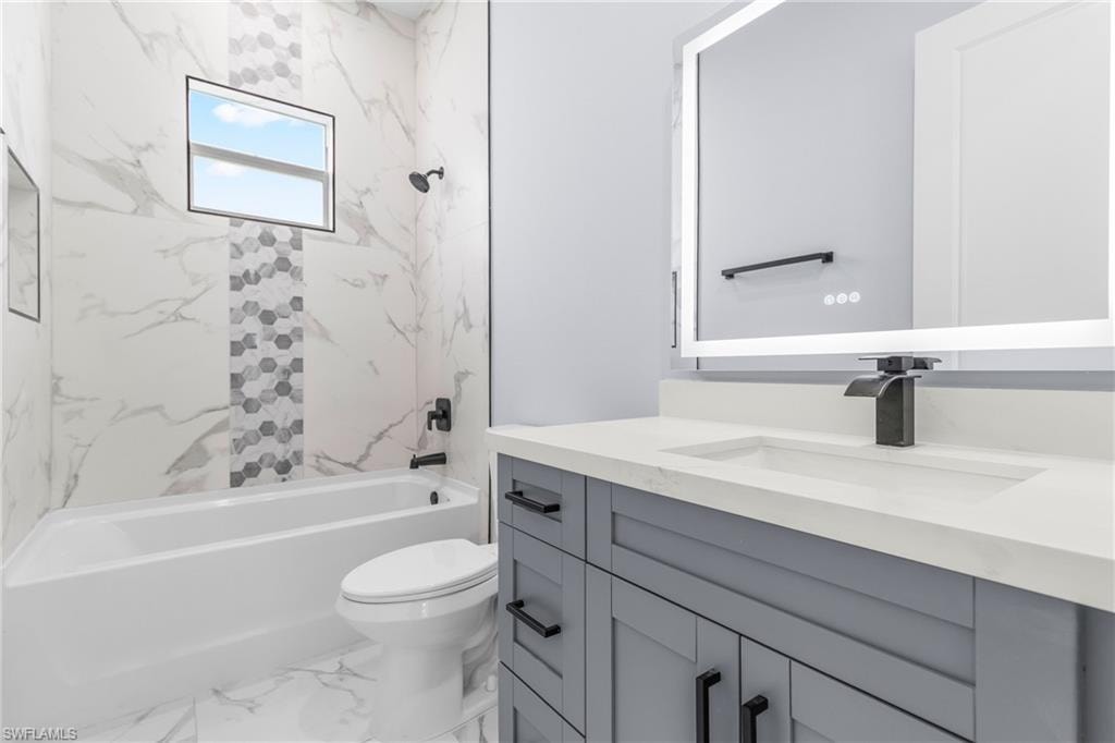 Bathroom with shower / bathtub combination, vanity, and marble finish floors
