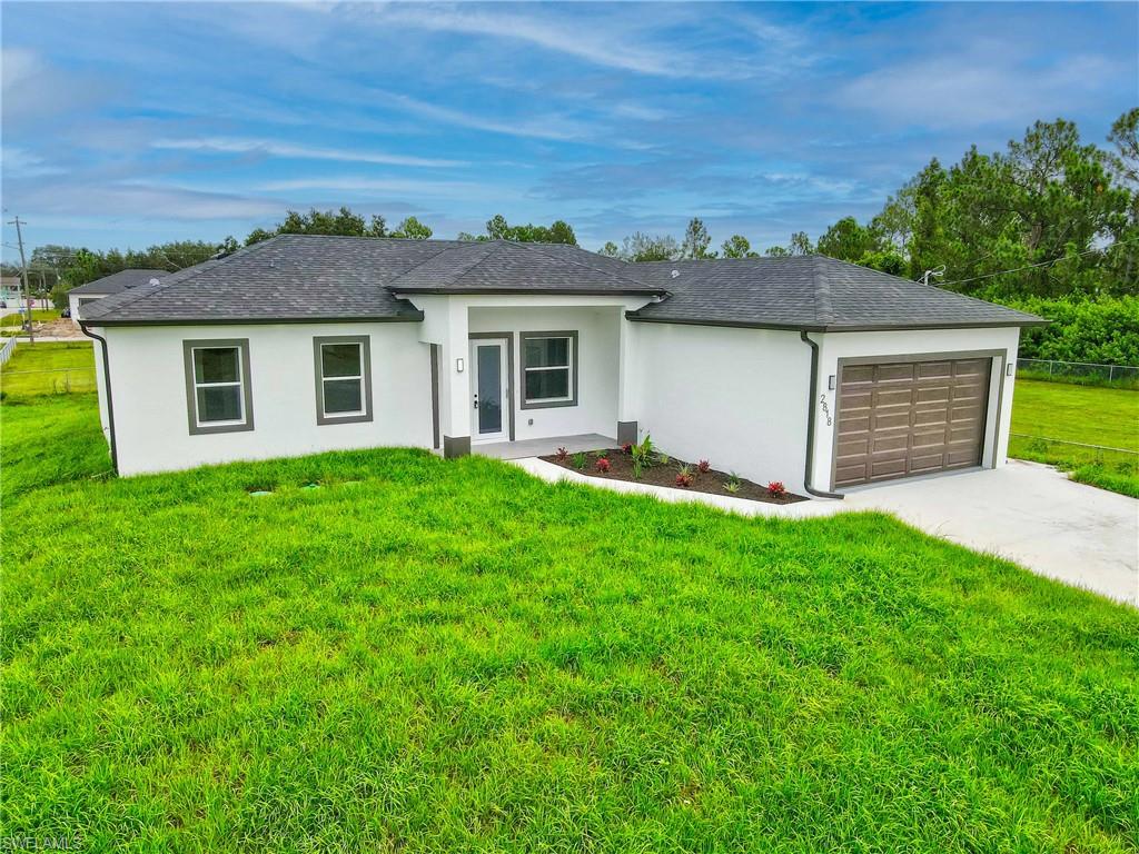 View of front of property with a garage, stucco siding, a front yard, and concrete driveway
