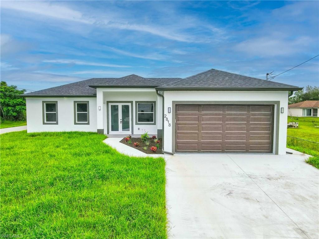 View of front of property with a front lawn, concrete driveway, stucco siding, a garage, and roof with shingles