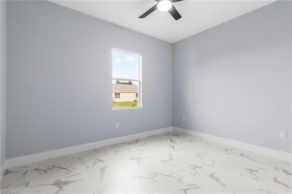 Spare room with marble finish floors and ceiling fan
