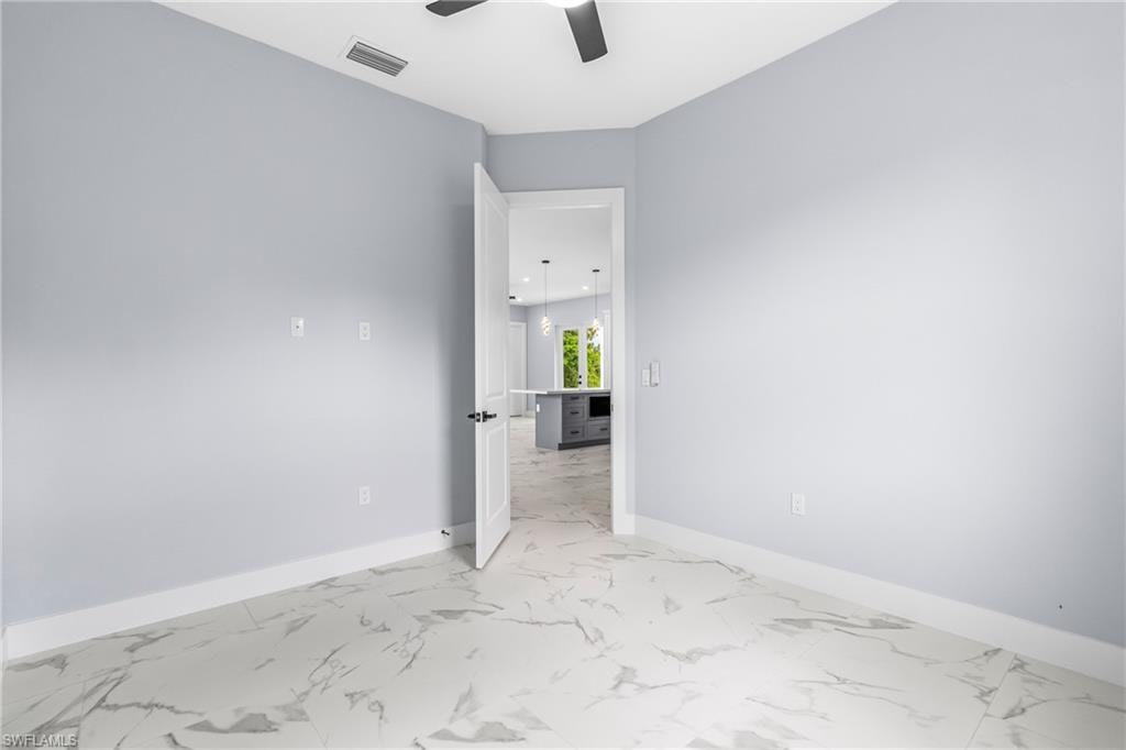 Unfurnished room with light marble finish floors and ceiling fan