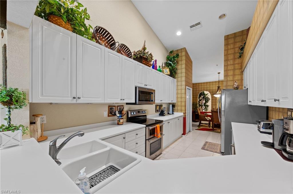 Kitchen featuring stainless steel appliances, white cabinetry, light countertops, recessed lighting, and light tile patterned flooring