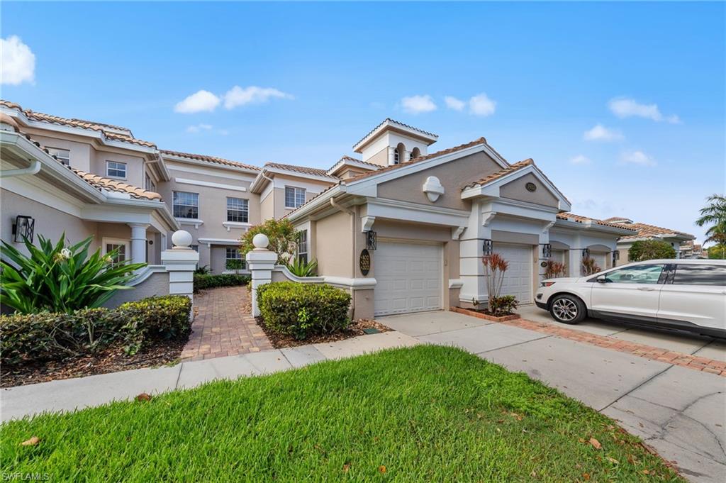 Mediterranean / spanish-style house with stucco siding, driveway, a tile roof, a garage, and a front lawn