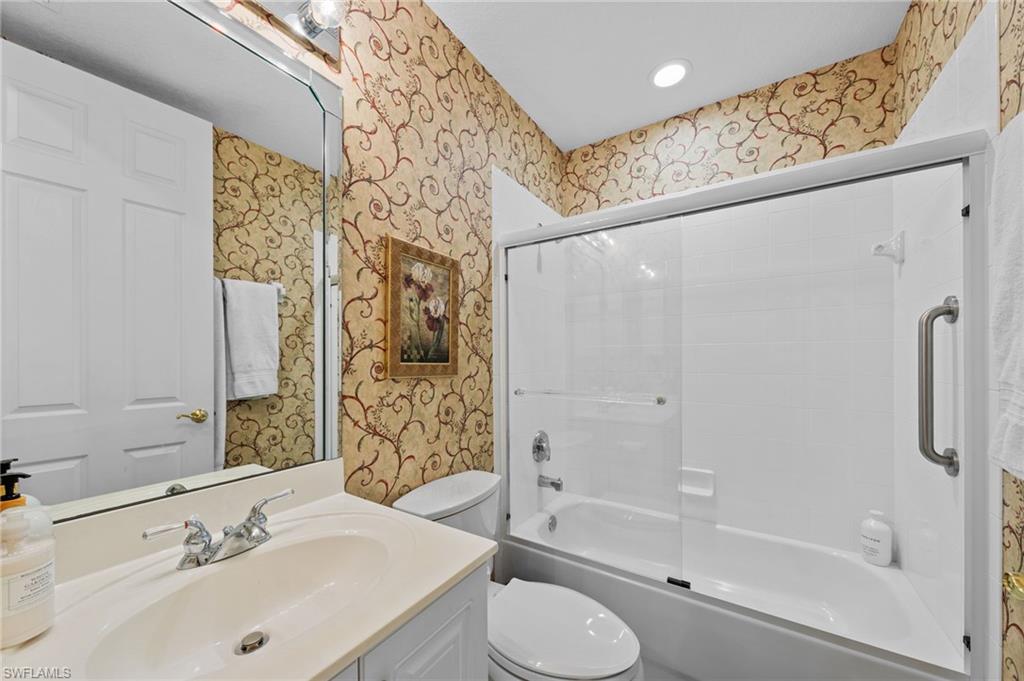 Bathroom with wallpapered walls, vanity, enclosed tub / shower combo, and recessed lighting