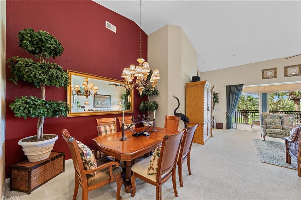 Dining area with vaulted ceiling, light carpet, and a chandelier