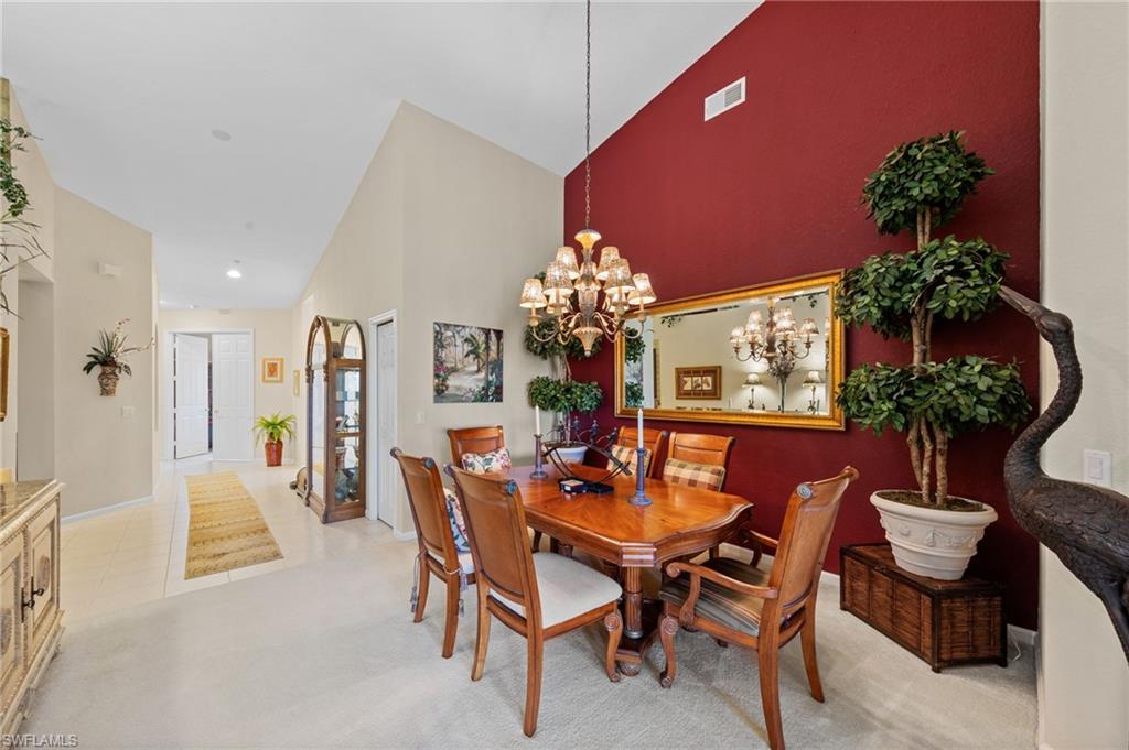 Dining space with vaulted ceiling, hanging lights, and light carpet