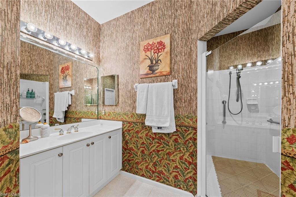 Bathroom featuring wallpapered walls, vanity, a stall shower, and light tile patterned floors
