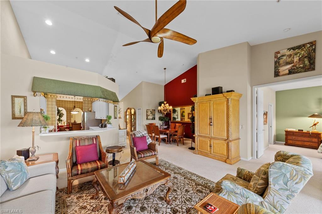 Living room featuring lofted ceiling, a ceiling fan, light colored carpet, and a chandelier