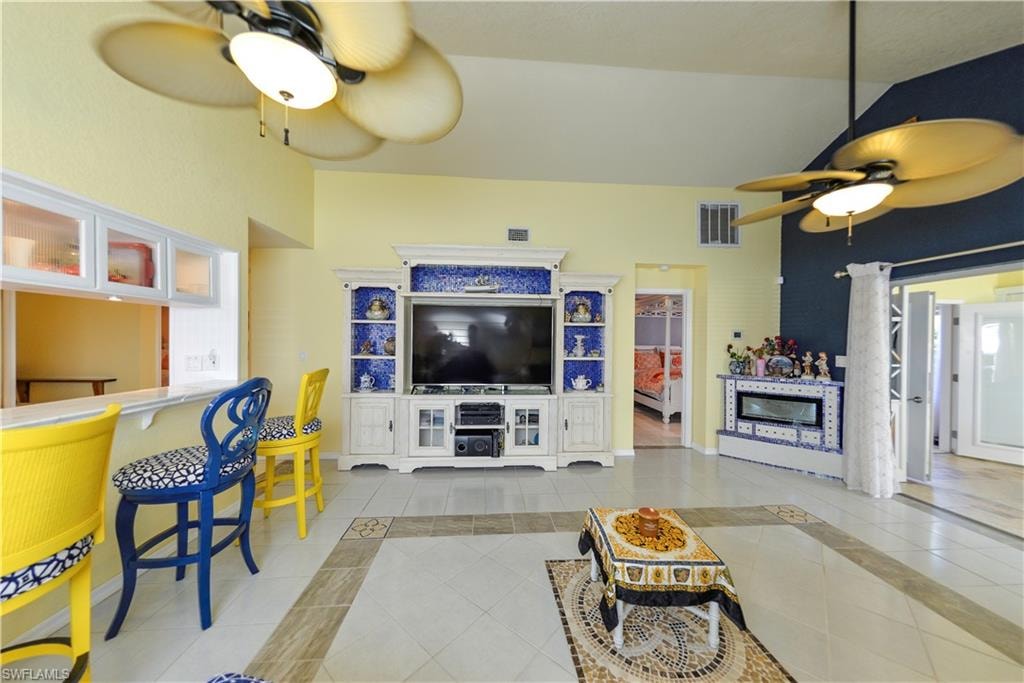 Spacious living area featuring high vaulted ceilings, multiple ceiling fans, and a built-in media center