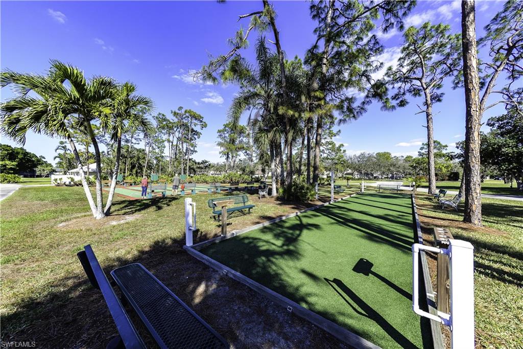 Bocce ball court with synthetic turf surface, surrounded by mature palm and pine trees