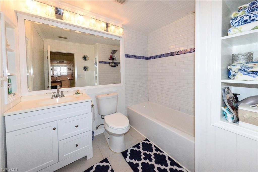 Bathroom featuring a white vanity with an integrated sink, a large mirror, and white subway tile in the tub/shower surround