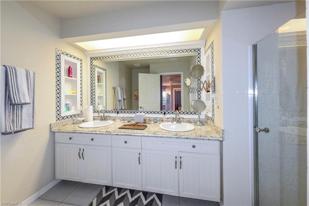 Bathroom featuring a double vanity with granite countertop, two undermount sinks, and white cabinetry