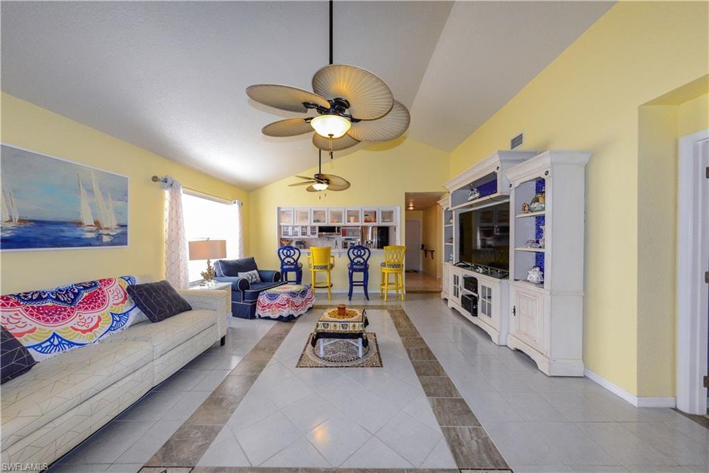 Living area featuring vaulted ceilings, patterned tile flooring, and multiple ceiling fans