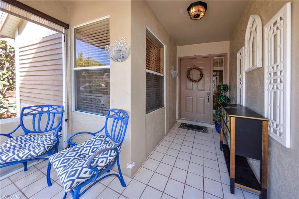 Covered porch entry featuring square tile flooring and a solid paneled door with a sidelight window