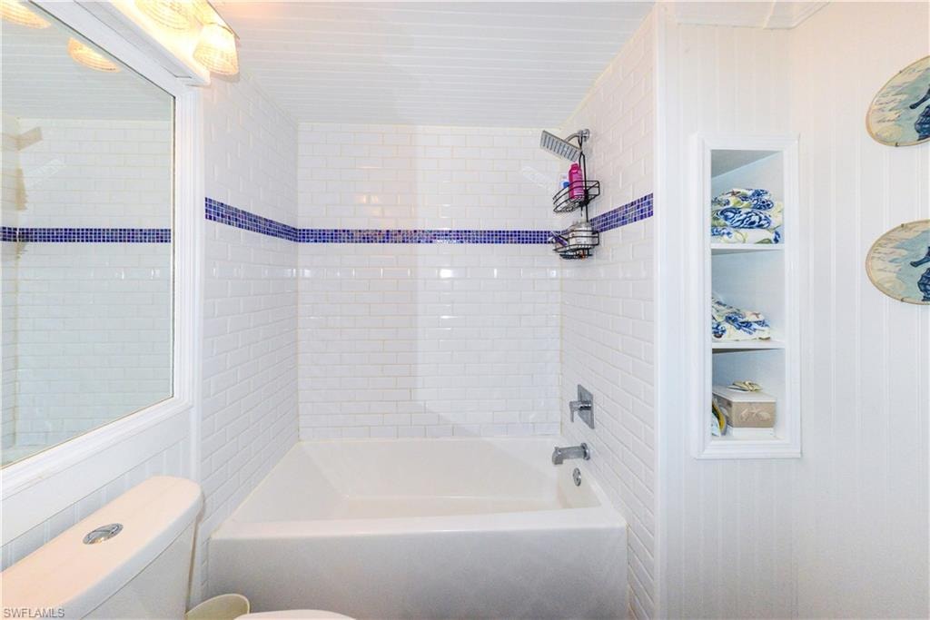 Tub/shower combination featuring white subway tile surround with a blue mosaic accent stripe
