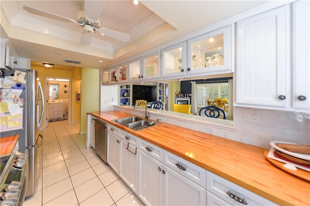 Kitchen featuring white cabinetry, wood-finish countertops, and a dual-basin sink