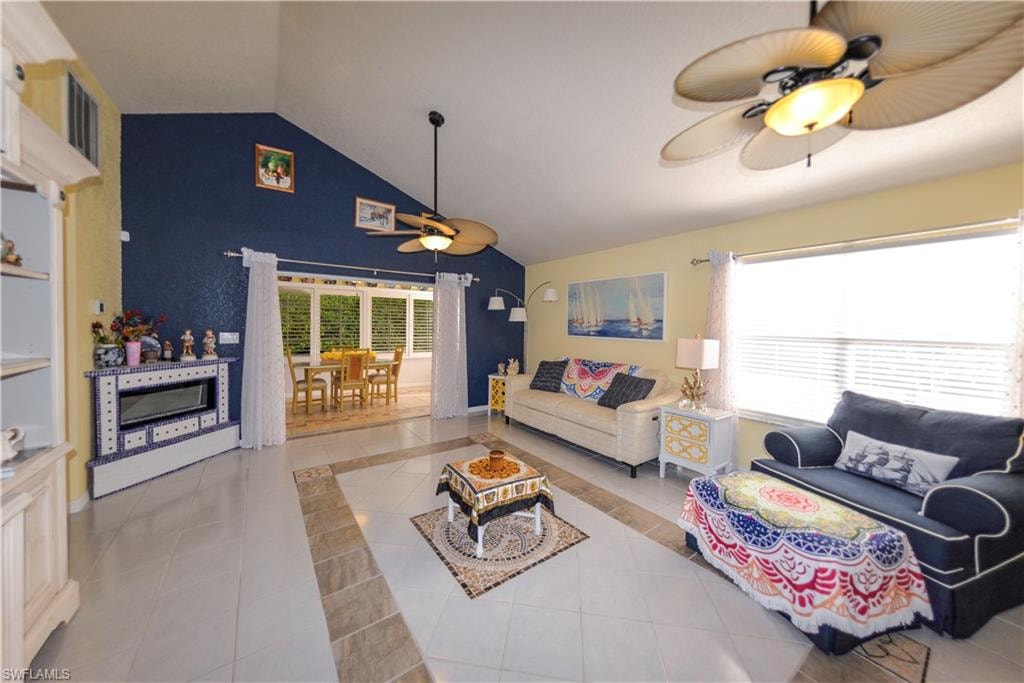 Vaulted ceilings accent a spacious living area featuring tiled flooring with a decorative inlay