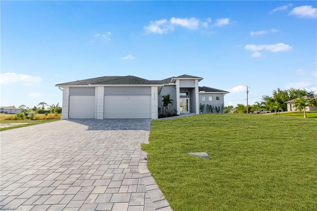 Prairie-style house with a front yard, a garage, decorative driveway, and stucco siding