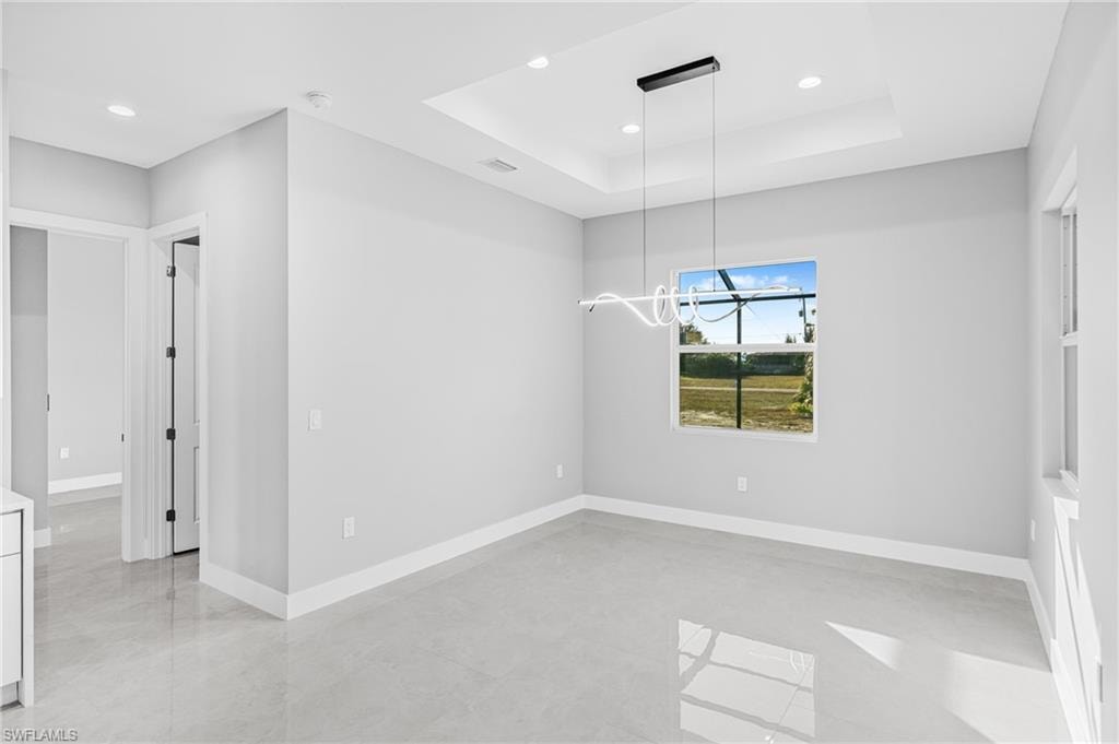 Unfurnished dining area with recessed lighting and a raised ceiling