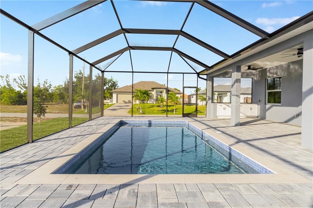 Swimming pool with glass enclosure, a yard, a sunroom, and a patio