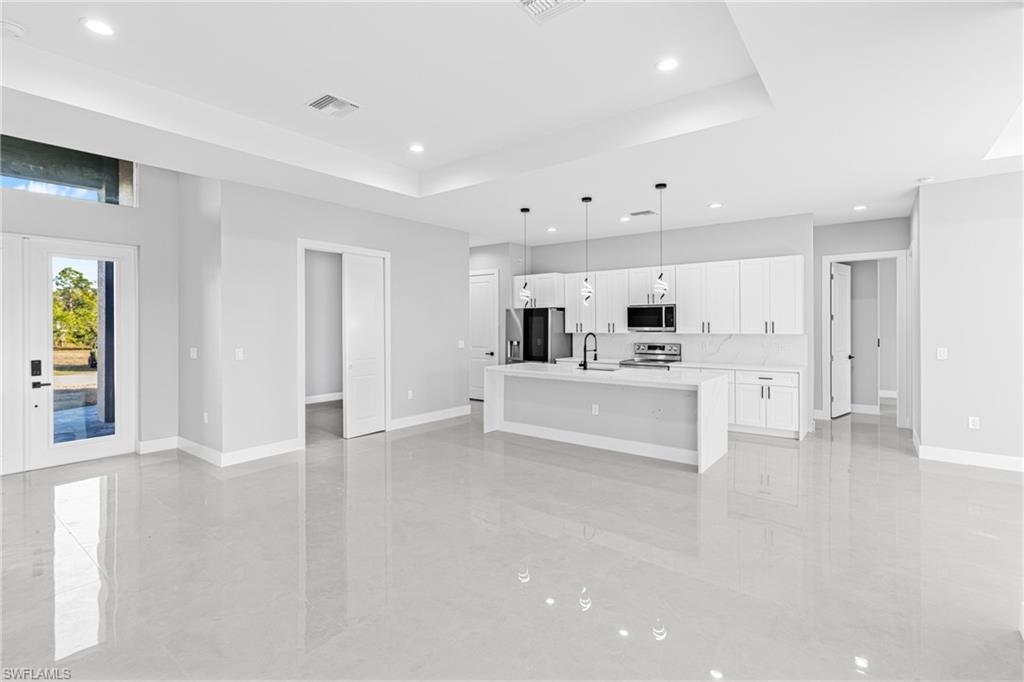 Unfurnished living room with french doors, a raised ceiling, and recessed lighting