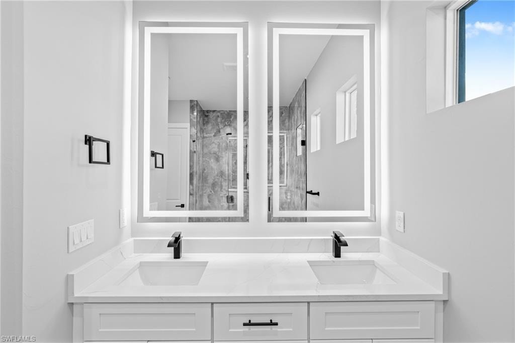 Bathroom featuring double vanity and a marble finish shower
