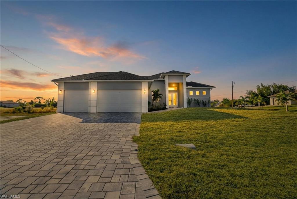 Prairie-style home featuring a garage, a front yard, decorative driveway, and stucco siding