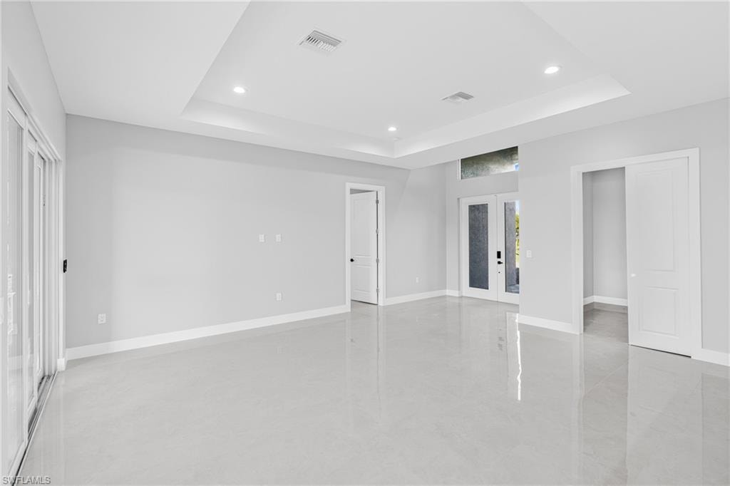 Unfurnished bedroom featuring access to exterior, french doors, concrete floors, recessed lighting, and a raised ceiling