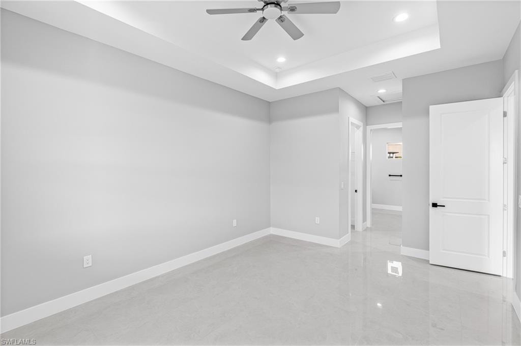 Spare room featuring a raised ceiling, recessed lighting, a ceiling fan, concrete floors, and attic access