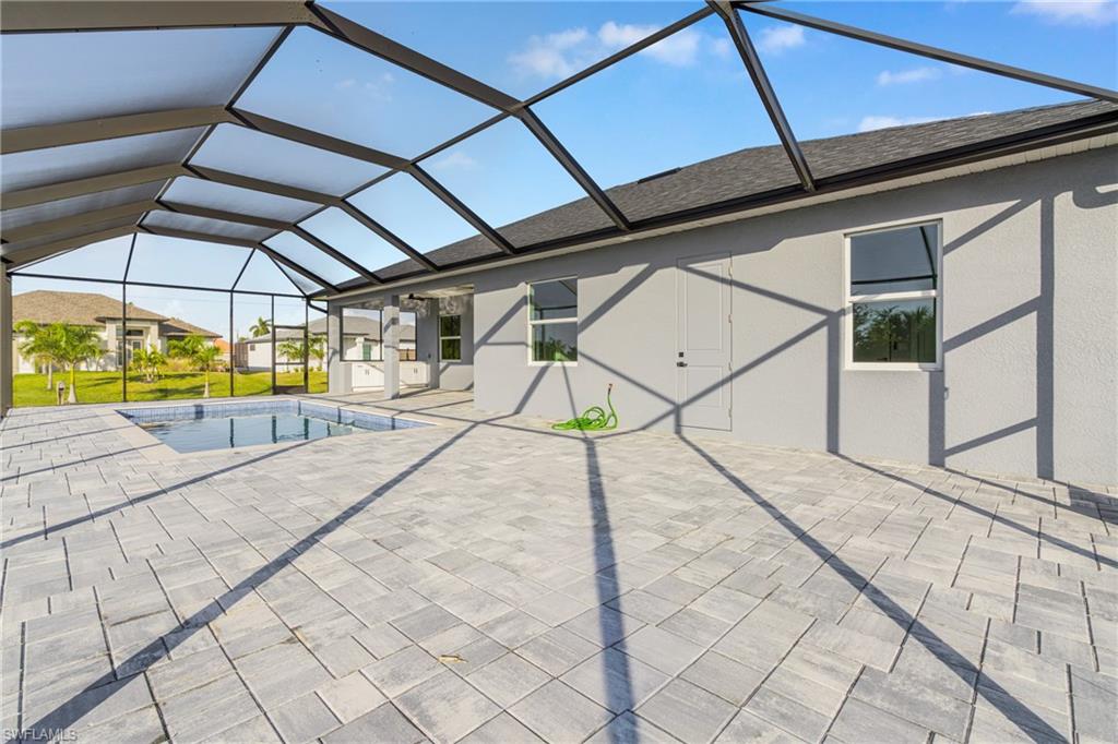 Swimming pool featuring a sunroom, glass enclosure, and a patio
