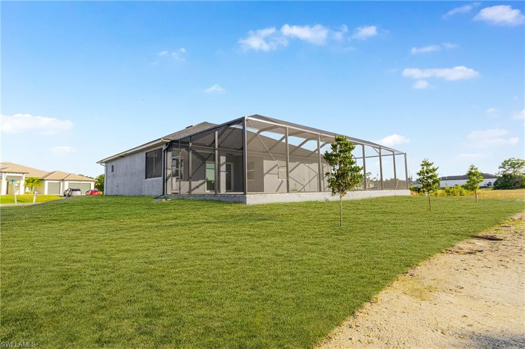 Back of house with a sunroom, glass enclosure, and a lawn