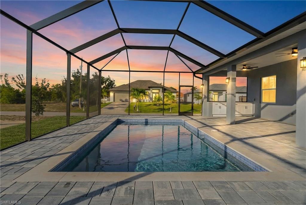 Outdoor pool with a lanai, a sunroom, an outdoor kitchen, and a patio