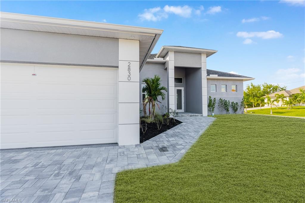 Contemporary house with a front lawn, stucco siding, and a garage