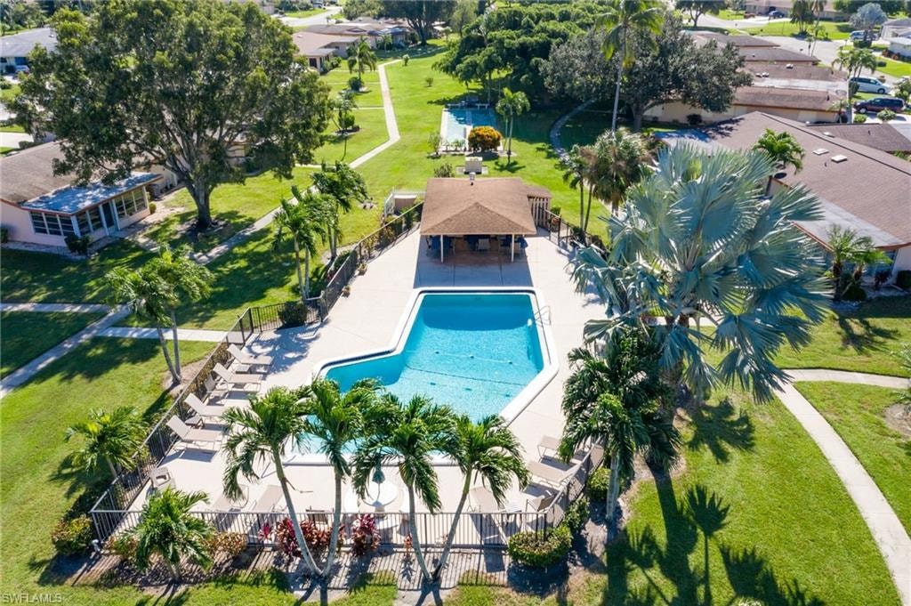 Fenced community pool with surrounding lounge chairs, shaded cabana area, and a large sun deck