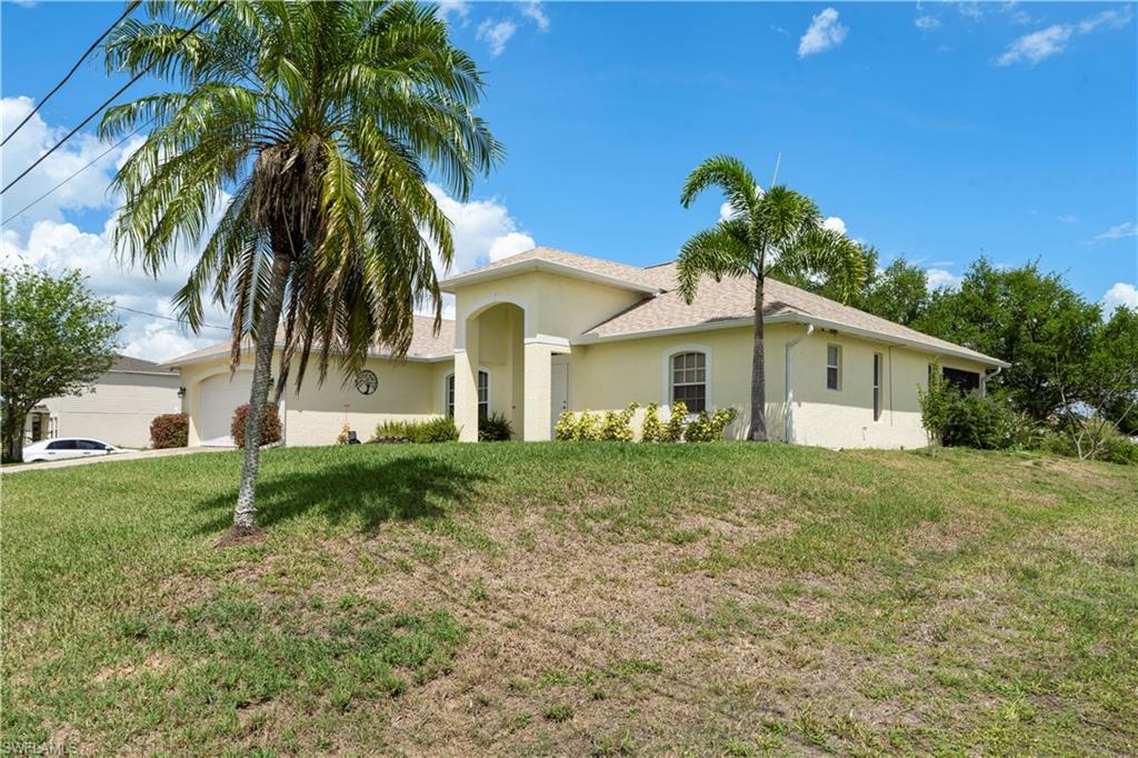 Ranch-style home with an attached garage, a front yard, and stucco siding