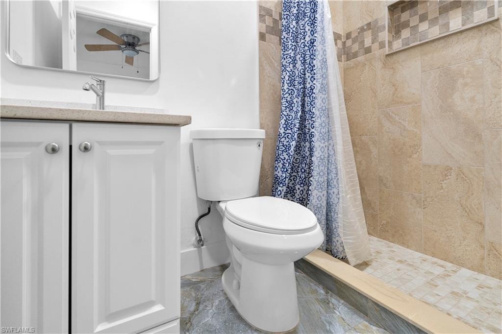 Full bathroom featuring vanity, a stall shower, and ceiling fan