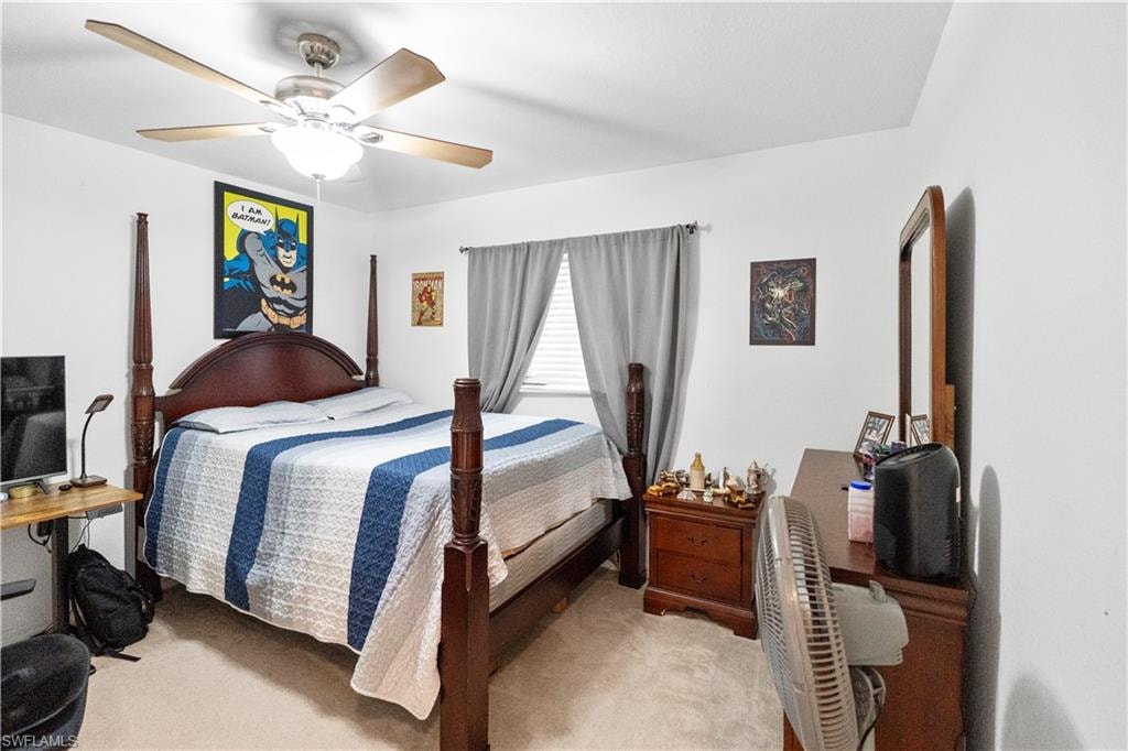 Bedroom with a ceiling fan and light colored carpet