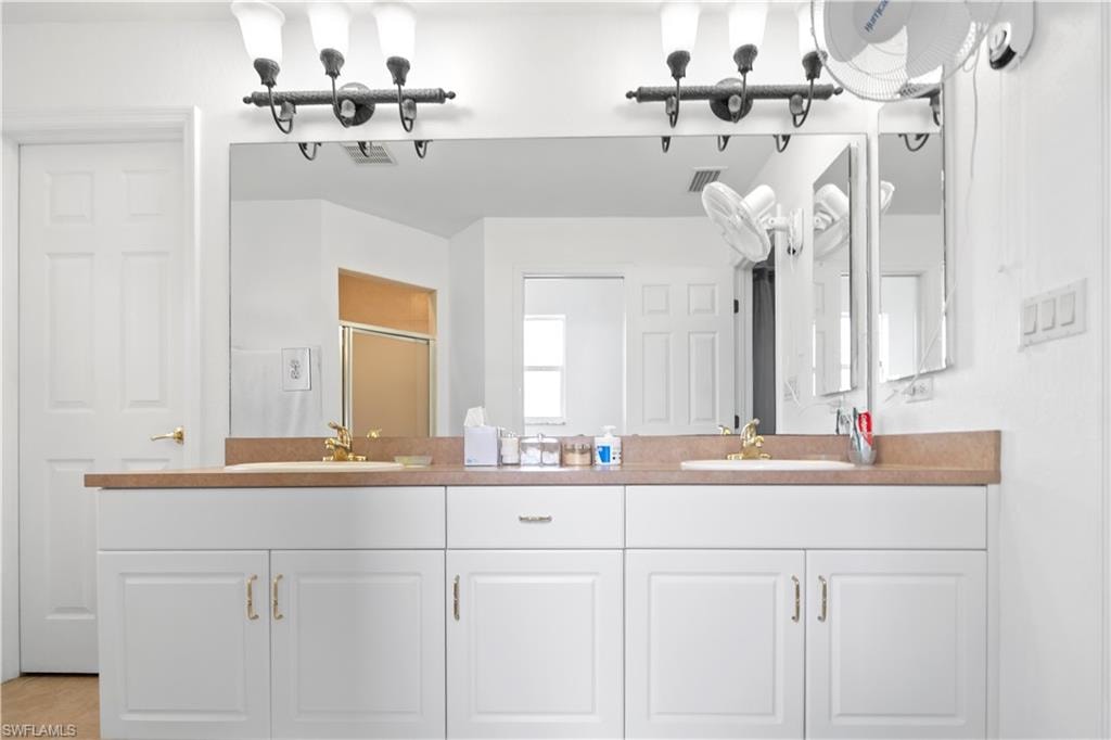 Full bath featuring double vanity and a stall shower