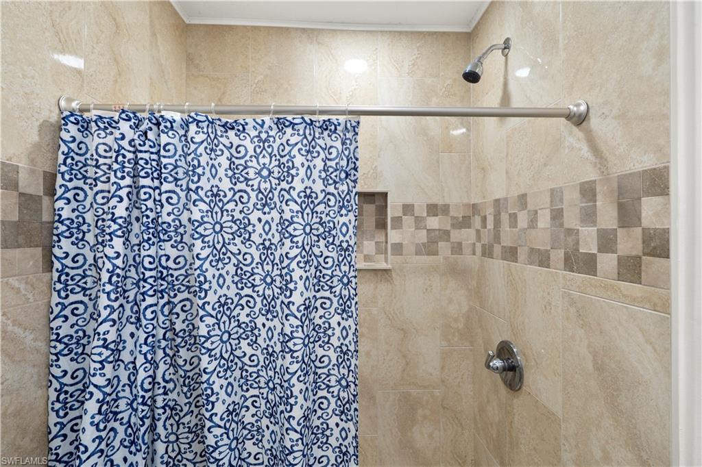 Full bath featuring a tile shower and crown molding