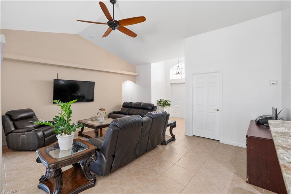 Living room featuring a ceiling fan, lofted ceiling, and light tile patterned floors